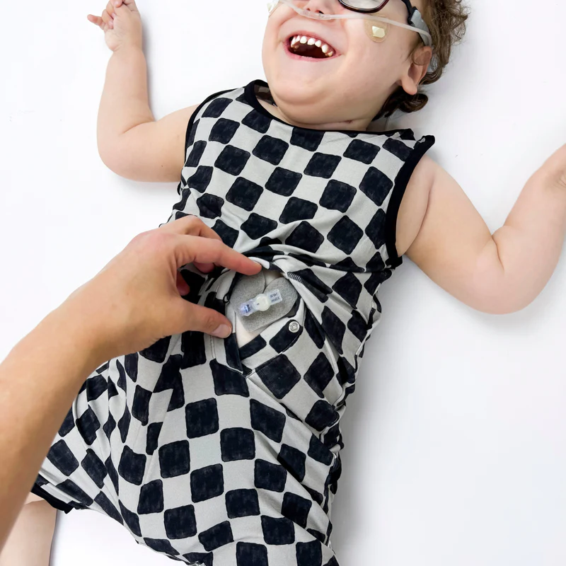 Girl wears black and grey checkered romper showing fastening